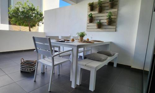 a white table and chairs with plants on the wall at Casilla de Costa, La Oliva in Villaverde