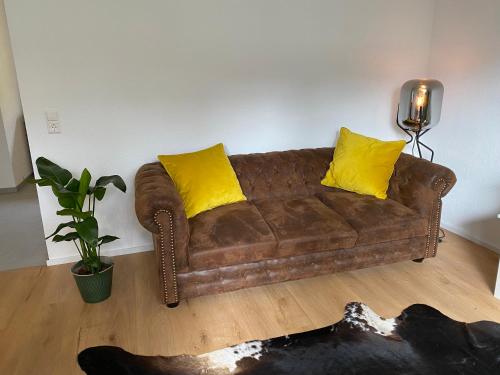 a brown couch with yellow pillows in a living room at Gemütliche Wohnung am Federsee in Bad Buchau
