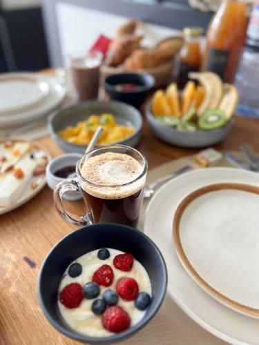 a table topped with cups of coffee and bowls of fruit at Le Gite de la Poterne, maison en bordure du Serein in Chablis