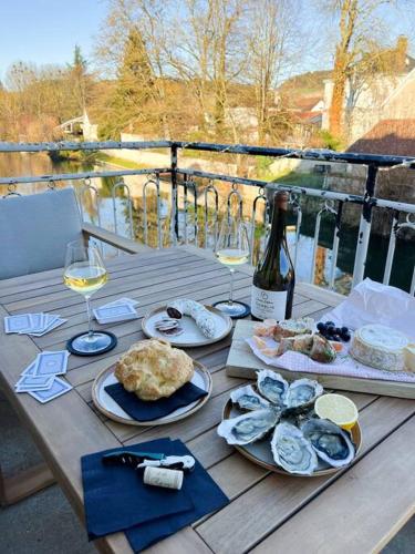 a wooden table with plates of food and wine at Le Gite de la Poterne, maison en bordure du Serein in Chablis