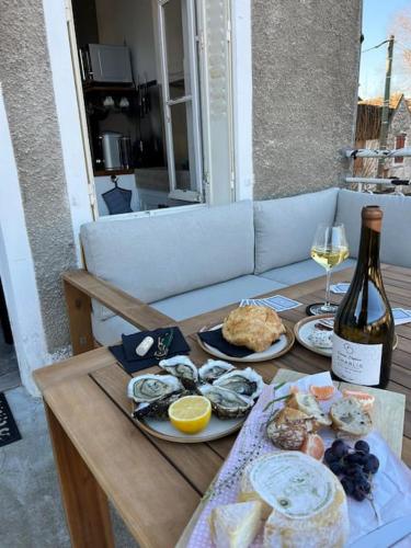 a table with plates of food and a bottle of wine at Le Gite de la Poterne, maison en bordure du Serein in Chablis