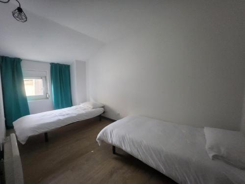 Cette chambre comprend deux lits et une fenêtre avec des rideaux verts. dans l'établissement Spacieux 2 chambres, paisible, à Bar-le-Duc