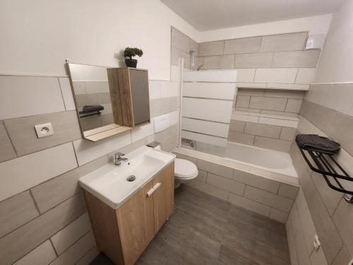 een badkamer met een wastafel, een toilet en een bad bij Spacieux 2 chambres, paisible in Bar-le-Duc