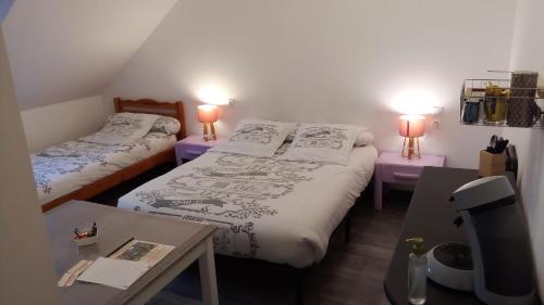 dwa łóżka w pokoju z dwoma stołami i dwoma lampami w obiekcie Le Relais de Jeanne w mieście Orbigny