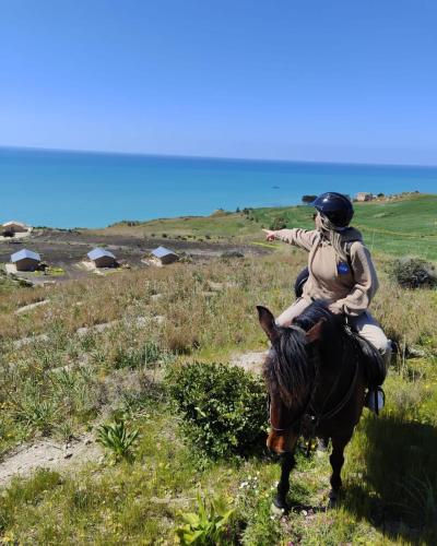 a woman riding on a horse in a field at Tendu' Punta Bianca Glamping Camp in Palma di Montechiaro