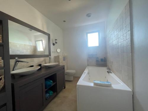 ein Badezimmer mit einer Badewanne, einem Waschbecken und einem Spiegel in der Unterkunft Magnifique villa récente entre mer et montagne située entre Ajaccio et Porticcio in Cauro