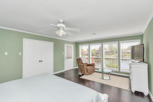 a bedroom with a bed and a chair and windows at Beauty on the Water! Lake House near the beaches! in Galveston
