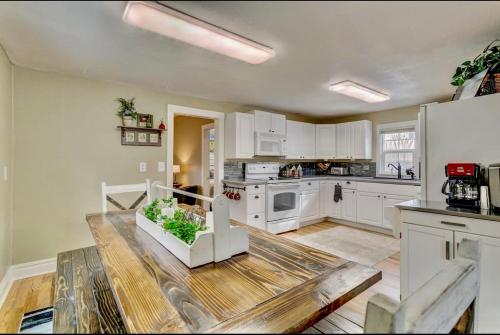 a kitchen with white cabinets and a wooden table at The Historic Blue Bird Cottage in Colorado Springs
