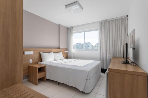 1 dormitorio con 1 cama blanca grande y escritorio en Flat Barra Da Tijuca, en Río de Janeiro