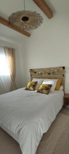 1 dormitorio con 1 cama blanca grande con almohadas en Au Cabanon, en Saint-Laurent-dʼAigouze