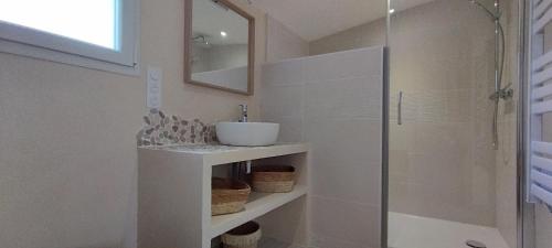 La salle de bains blanche est pourvue d'un lavabo et d'une douche. dans l'établissement Au Cabanon, à Saint-Laurent-dʼAigouze