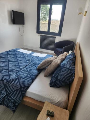 a bedroom with a bed and a chair and a window at LOCATION T2 in Chenac-sur-Gironde