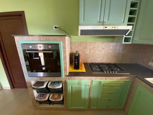 Una cocina con gabinetes verdes y una estufa. horno superior en VILLA DELLE POMELIE, en Isola delle Femmine