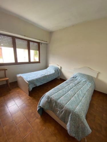 1 dormitorio con 2 camas y 2 ventanas en La Quinta - Casa de Campo Balcarce en Balcarce