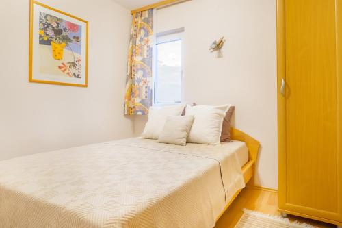 um quarto com uma cama com lençóis brancos e uma janela em Apartman 3 em Omišalj