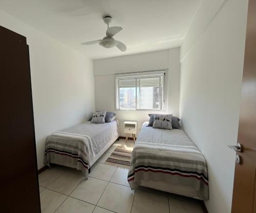 a bedroom with two beds and a window at Apartamento 2 quartos completo 200 m da praia in Capão da Canoa