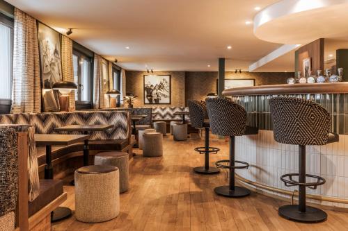 a restaurant with leather seats and a bar at Hotel Valaisia Crans Montana, a Faern Collection Resort in Crans-Montana
