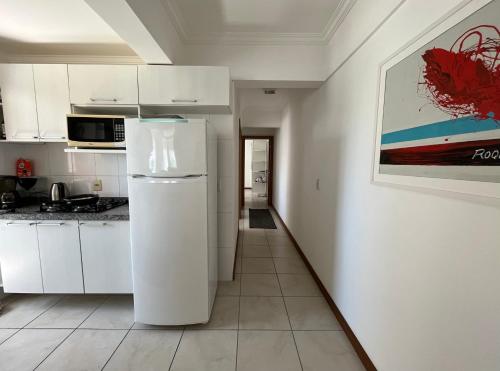 a white kitchen with a refrigerator in a room at Apartamento 2 quartos completo 200 m da praia in Capão da Canoa