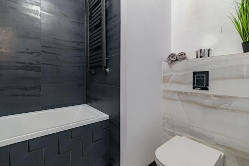 a bathroom with a white tub and a toilet at Villa Garden Jagiellończyka in Olsztyn