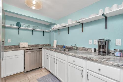 a large kitchen with white cabinets and blue walls at Galveston Studio - Sleeps 7 - Minutes to Beach !! in Galveston