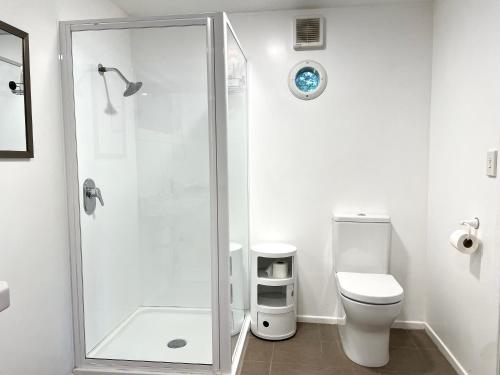 a white bathroom with a shower and a toilet at Waiheke Onetangi Close to Beach in Onetangi