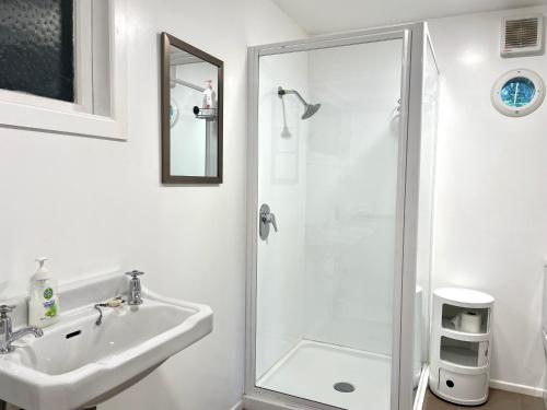a white bathroom with a shower and a sink at Waiheke Onetangi Close to Beach in Onetangi