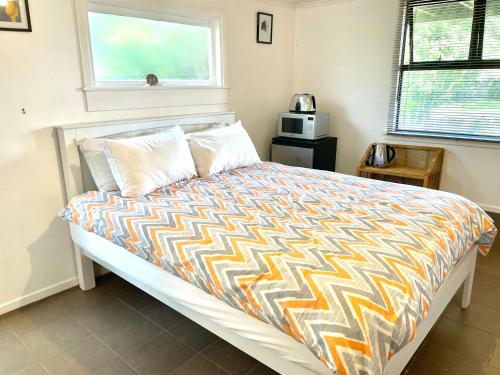 a bedroom with a bed with a colorful comforter at Waiheke Onetangi Close to Beach in Onetangi