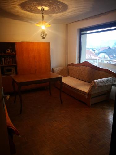 uma sala de estar com um sofá, uma mesa e uma janela em Stanovanje v Žalcu em Žalec