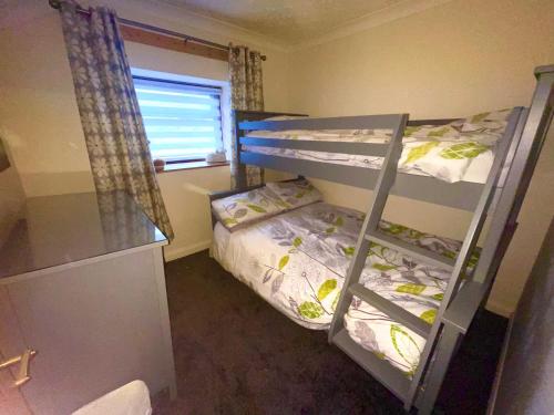 a bedroom with two bunk beds and a window at Slate Mountain Cottage near zip world snowdonia in Tanygrisiau