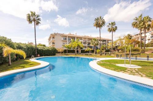 una gran piscina con palmeras y un edificio en Lorcrimar 3 Apto cerca de la playa con piscina, en Marbella