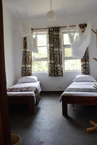a room with two beds and two windows at Themi View in Arusha