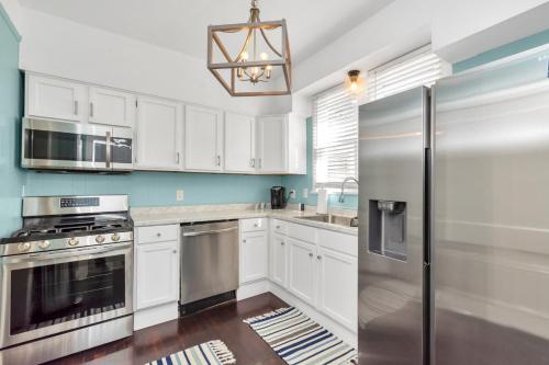 a kitchen with white cabinets and a stainless steel refrigerator at 2 Kitchens,2 Living Rooms,4 Bedrooms-Close to all! in Galveston