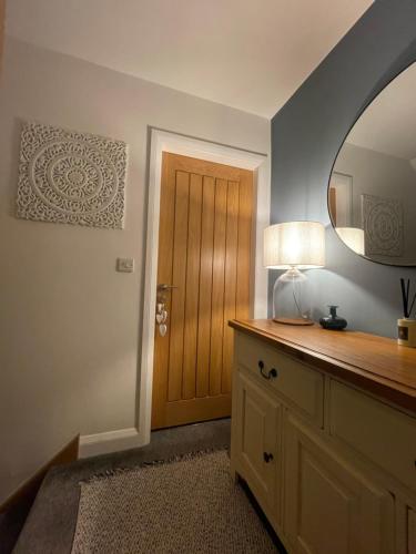 a room with a mirror and a table with a lamp at Abbey’s Inn in Cheadle