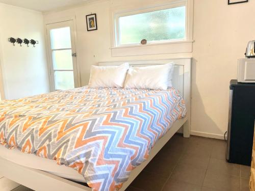 a bedroom with a bed with a colorful comforter and a window at Waiheke Onetangi Close to Beach in Onetangi