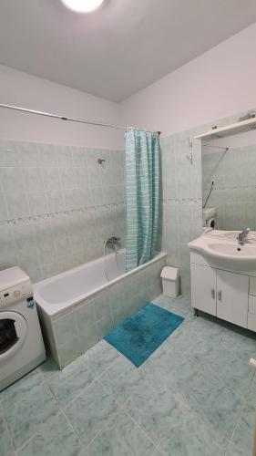 un bagno bianco con vasca e lavandino di Gabi Apartman a Hajdúszoboszló