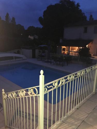 a white fence next to a swimming pool at night at Studio privé in Cazilhac