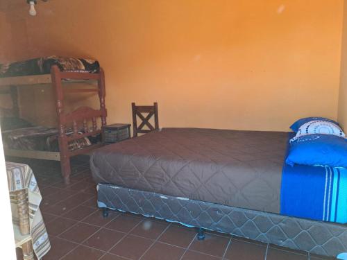 a bedroom with a bed and a chair in it at Carnavalito Hostel Tilcara in Tilcara