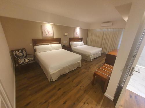 a hotel room with two beds and a chair at StradivariuS Hotel Boutique in Villa General Belgrano