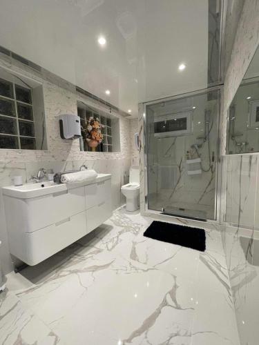 uma casa de banho branca com um chuveiro e um lavatório. em Chambre de luxe familiale 95 Bleu em Deuil-la-Barre