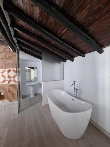 La salle de bains est pourvue d'une grande baignoire blanche et d'un lavabo. dans l'établissement Canaan Boutique Hotel Ronda, à Ronda