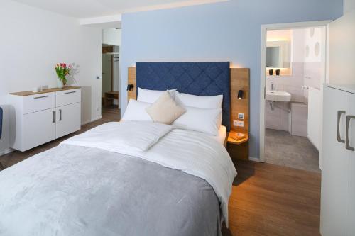 a bedroom with a large white bed and a bathroom at Minderleins Apart in Pottenstein