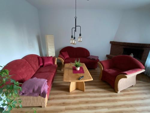 a living room with two red couches and a table at Ferienwohnungen Schierbaum in Lembruch