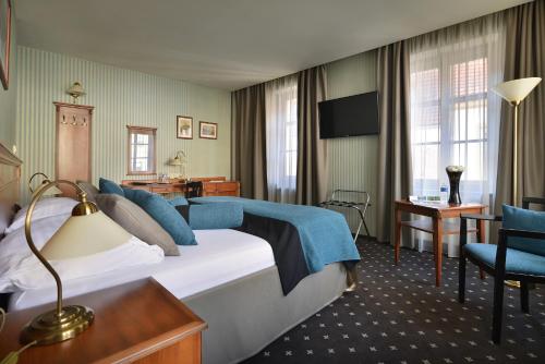 a hotel room with a large bed and a desk at City Hotel Morris in Česká Lípa