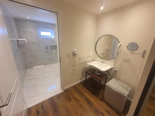 a bathroom with a shower and a sink and a mirror at StradivariuS Hotel Boutique in Villa General Belgrano