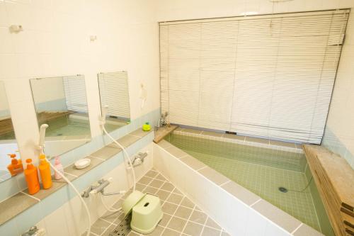 a bathroom with a tub and a swimming pool at 駅前山小屋A-yard in Ome