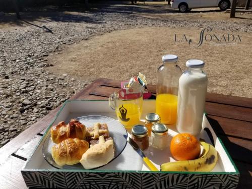 Una bandeja con un plato de comida y naranjas y jugo. en La Soñada Cabañas & Spa, en Merlo