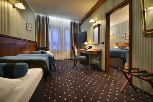 a hotel room with two beds and a desk at City Hotel Morris in Česká Lípa