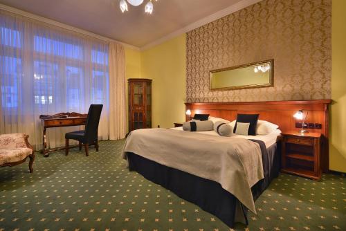 a hotel room with a bed and a desk and a piano at City Hotel Morris in Česká Lípa