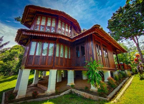 a wooden house in the middle of a yard at Orangutan Bungalow in Bukit Lawang