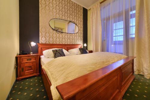 a bedroom with a large bed and a mirror at City Hotel Morris in Česká Lípa
